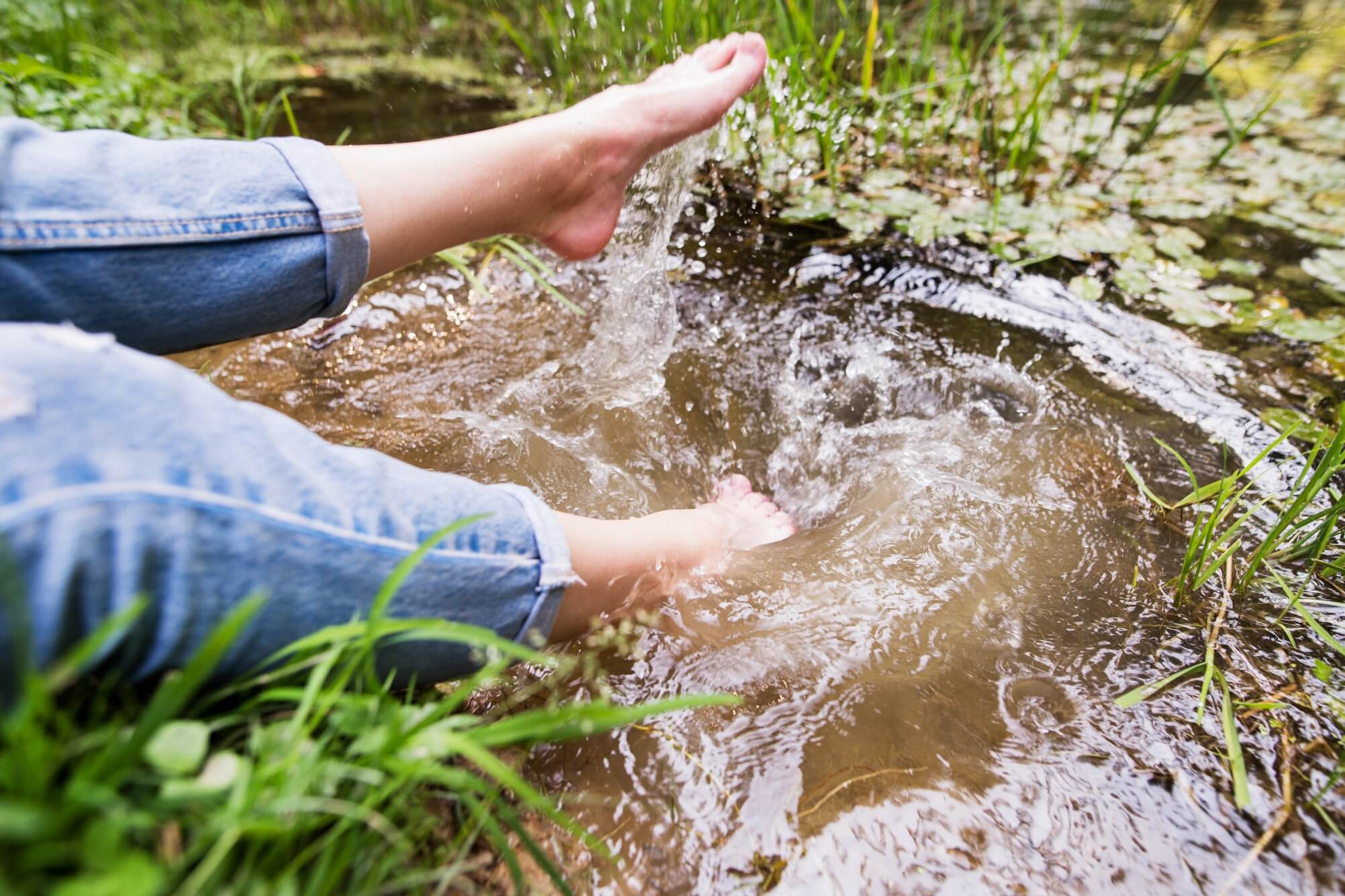 feet of unrecognizable woman sitting at the lake PTR6BSU